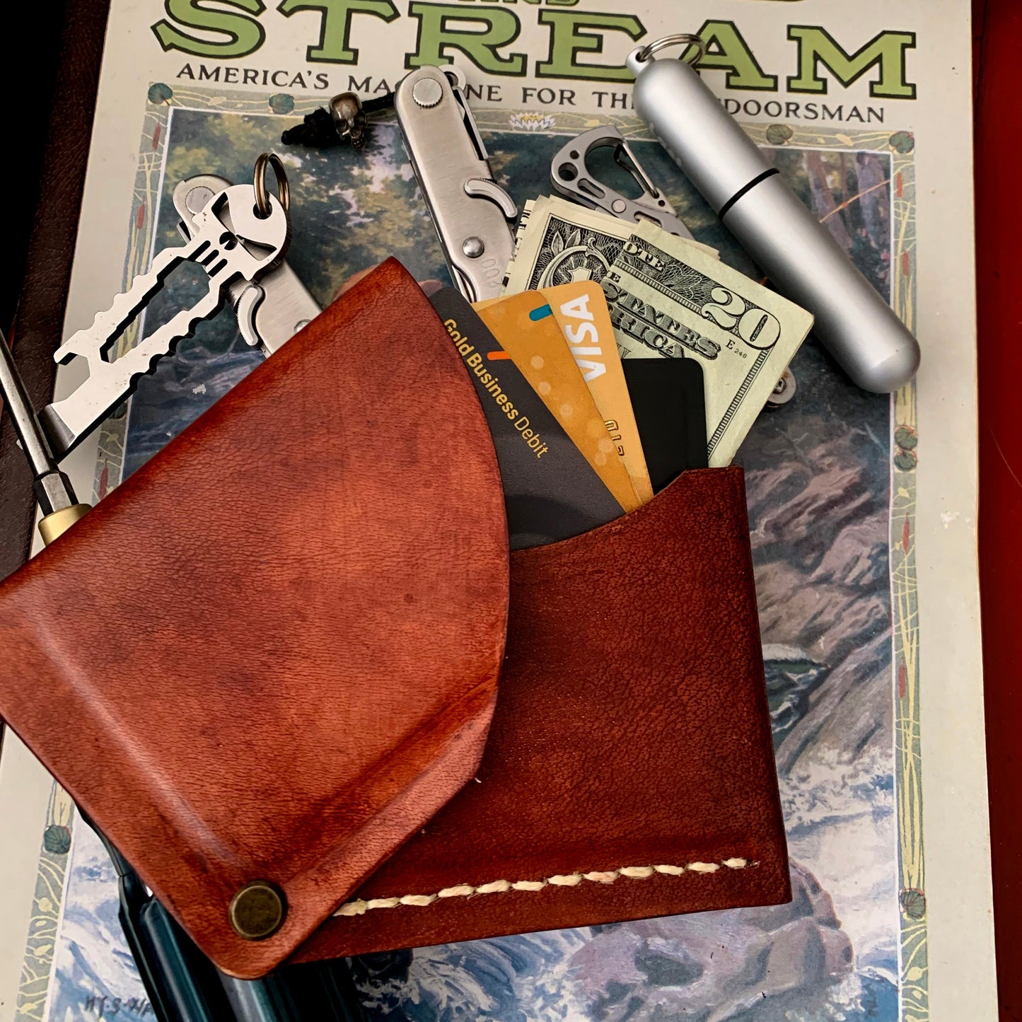 Brown leather wallet with keys and money on a 'Field and Stream' magazine